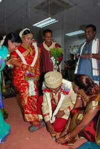 Putting toe rings on his bride in traditional Wedding